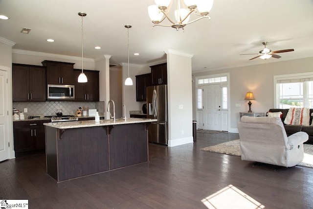 kitchen with a breakfast bar, decorative light fixtures, stainless steel appliances, and a kitchen island with sink