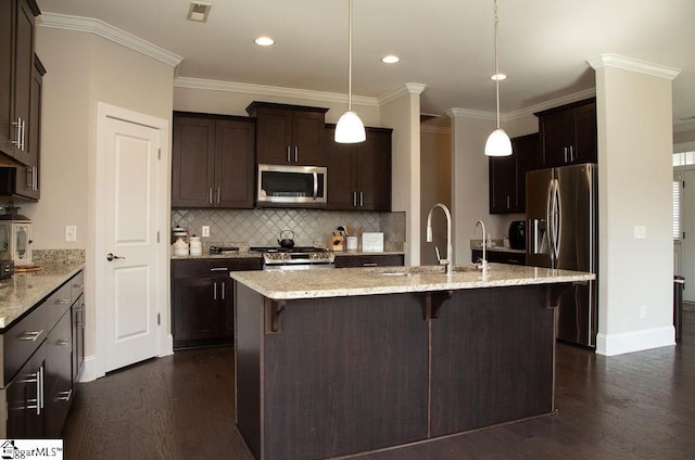 kitchen featuring light stone countertops, dark hardwood / wood-style flooring, decorative light fixtures, appliances with stainless steel finishes, and ornamental molding