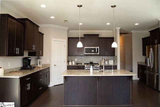 kitchen with dark wood-type flooring, an island with sink, appliances with stainless steel finishes, decorative light fixtures, and dark brown cabinets