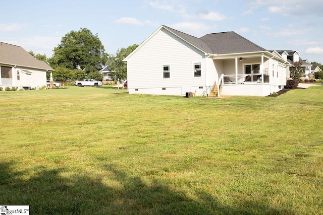 back of property with a porch, a yard, and ceiling fan