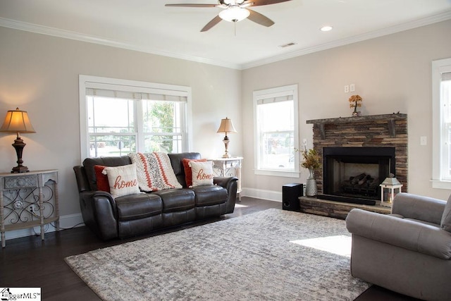 living room featuring dark hardwood / wood-style floors, ceiling fan, a stone fireplace, and ornamental molding