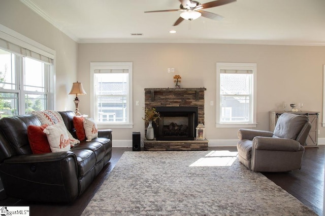 living room with dark hardwood / wood-style floors, ceiling fan, a stone fireplace, and ornamental molding