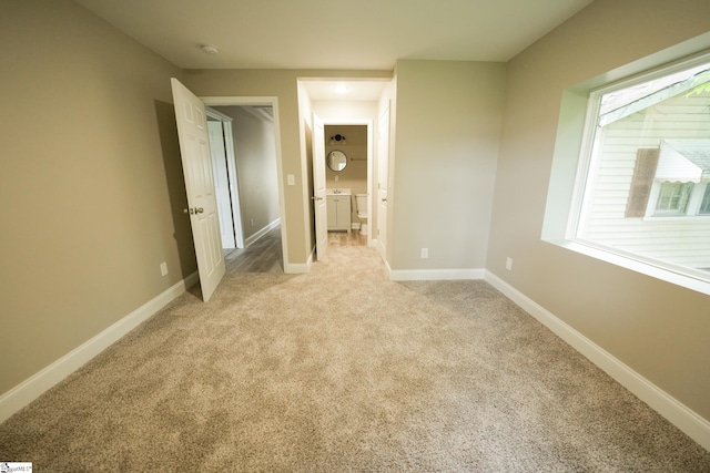 unfurnished bedroom with washing machine and dryer, light colored carpet, and multiple windows