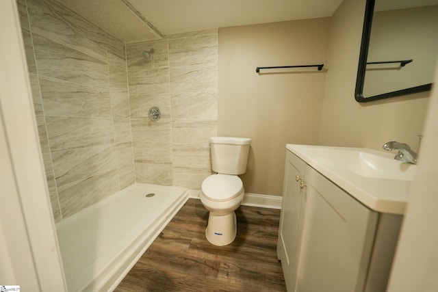 bathroom with tiled shower, hardwood / wood-style floors, vanity, and toilet