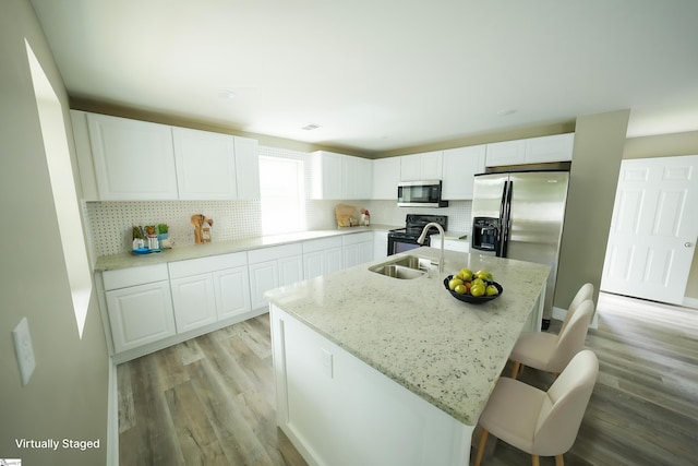 kitchen featuring white cabinets, a center island with sink, and appliances with stainless steel finishes