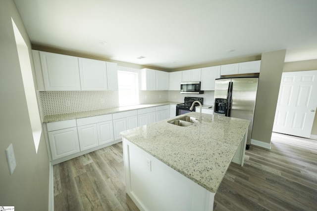 kitchen featuring a center island with sink, decorative backsplash, white cabinetry, and appliances with stainless steel finishes