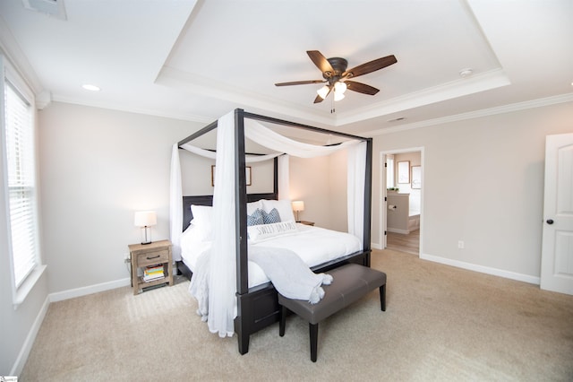 bedroom with ceiling fan, light colored carpet, ornamental molding, and a tray ceiling