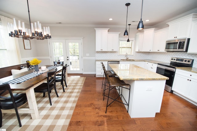 kitchen with pendant lighting, a kitchen island, sink, and appliances with stainless steel finishes