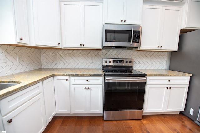 kitchen with white cabinets, light stone countertops, stainless steel appliances, and tasteful backsplash