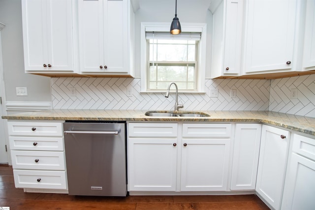 kitchen featuring tasteful backsplash, stainless steel dishwasher, sink, pendant lighting, and white cabinetry