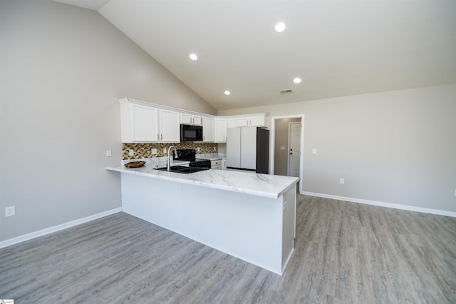 kitchen with high vaulted ceiling, black appliances, white cabinets, tasteful backsplash, and kitchen peninsula