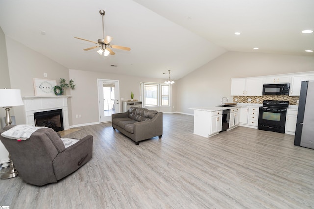 living room with light hardwood / wood-style floors, vaulted ceiling, ceiling fan, and sink