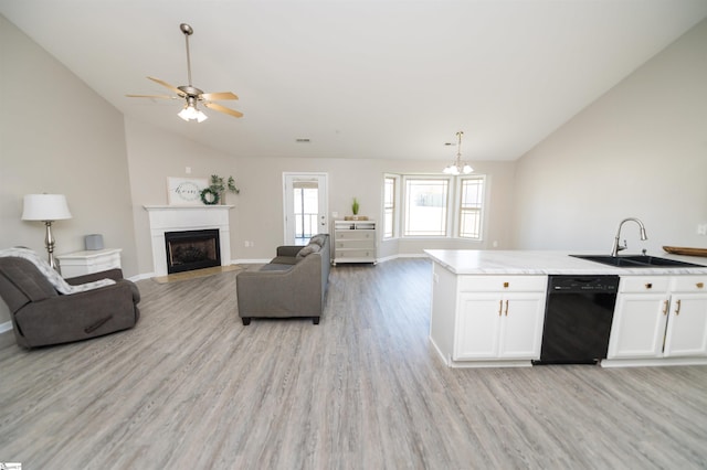 kitchen with sink, black dishwasher, lofted ceiling, white cabinets, and light wood-type flooring