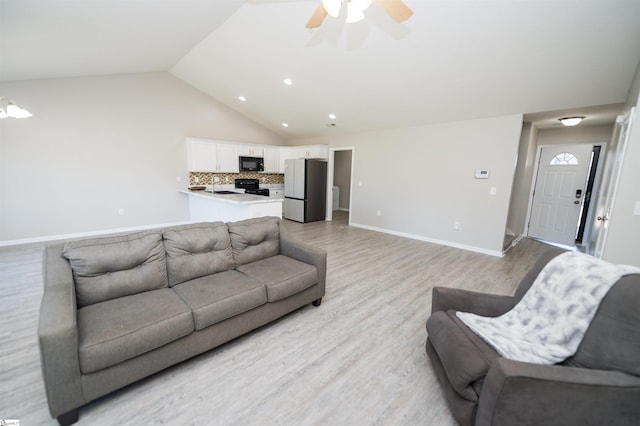 living room with ceiling fan, light hardwood / wood-style floors, and lofted ceiling