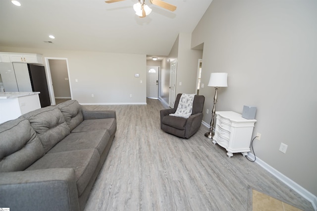 living room featuring ceiling fan, light hardwood / wood-style flooring, and vaulted ceiling