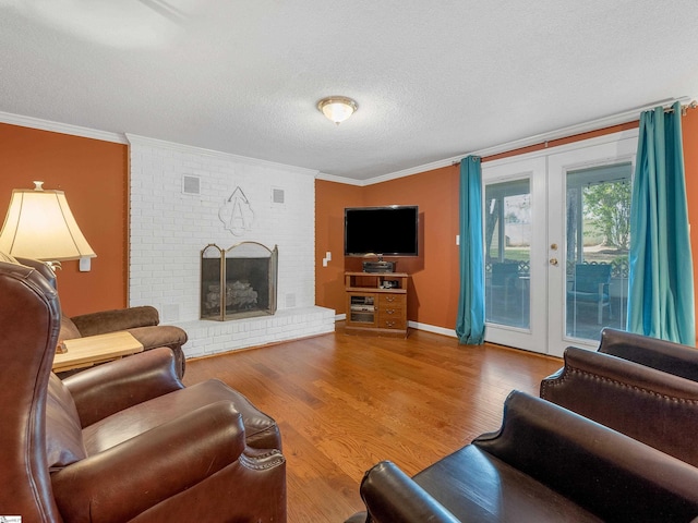 living room featuring french doors, a brick fireplace, ornamental molding, a textured ceiling, and hardwood / wood-style flooring