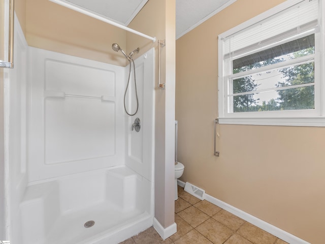 bathroom featuring tile patterned flooring, toilet, walk in shower, and crown molding