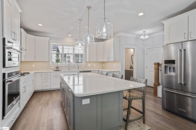 kitchen with stainless steel appliances, a kitchen island, pendant lighting, dark hardwood / wood-style floors, and white cabinetry