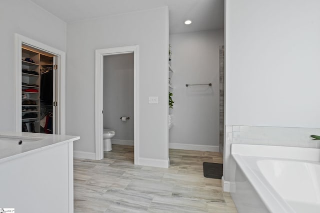 bathroom featuring a washtub, vanity, and toilet