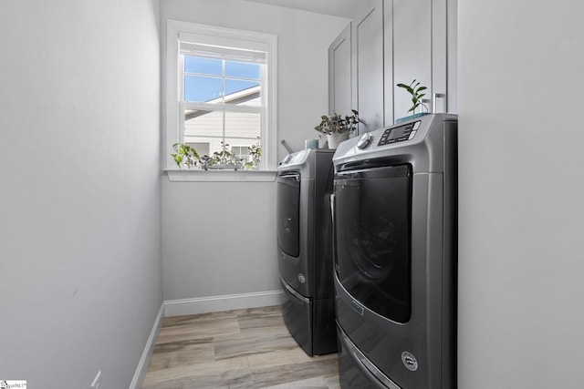 clothes washing area with independent washer and dryer and light hardwood / wood-style flooring