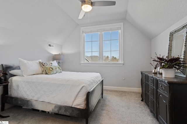 bedroom featuring ceiling fan, light colored carpet, lofted ceiling, and a textured ceiling