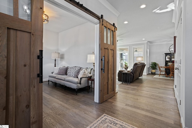 entrance foyer featuring light wood-type flooring, a barn door, and ornamental molding