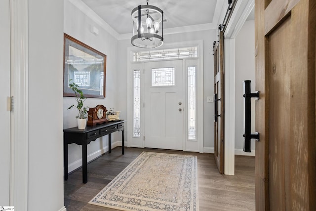 foyer with hardwood / wood-style flooring, a barn door, ornamental molding, and a chandelier