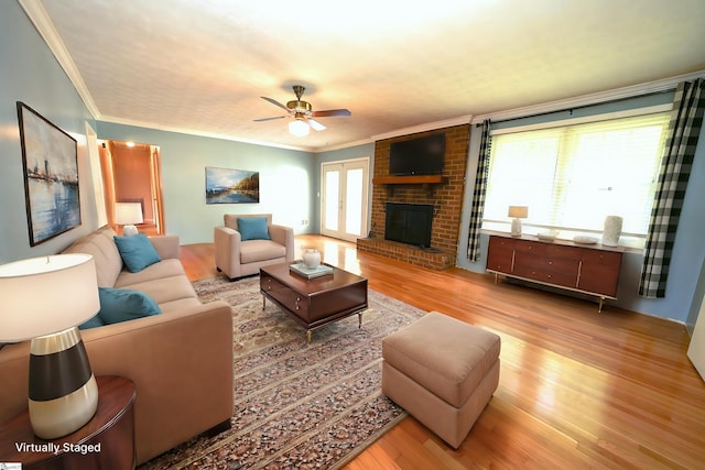 living room featuring hardwood / wood-style flooring, crown molding, a wealth of natural light, and a brick fireplace