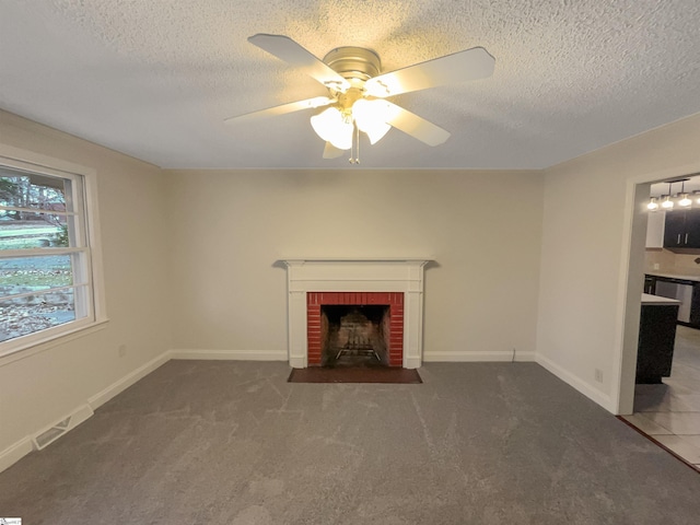 unfurnished living room featuring ceiling fan, a fireplace, dark carpet, and a textured ceiling