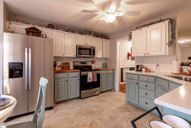 kitchen featuring appliances with stainless steel finishes, a textured ceiling, gray cabinets, and white cabinetry