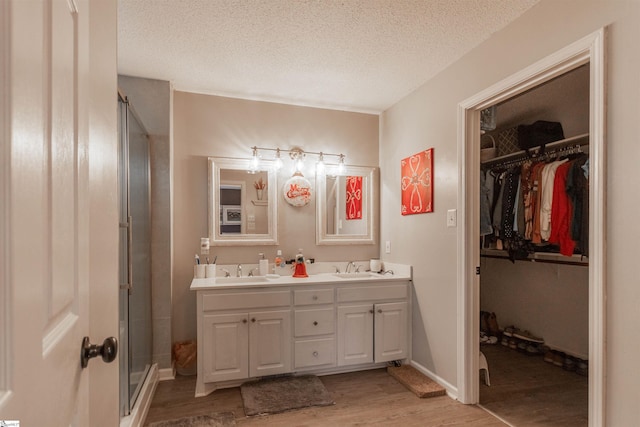 bathroom with hardwood / wood-style floors, vanity, a textured ceiling, and a shower with shower door