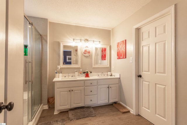 bathroom with vanity, wood-type flooring, a textured ceiling, and an enclosed shower