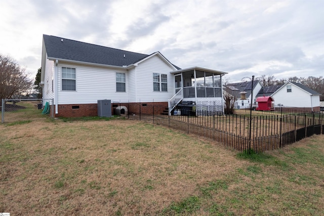 rear view of house with a lawn, a sunroom, and central AC unit