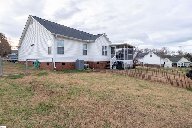 rear view of property with a lawn, a sunroom, and central AC unit