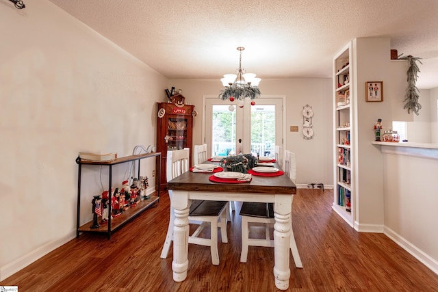 dining area featuring a textured ceiling, a notable chandelier, dark wood-type flooring, and french doors