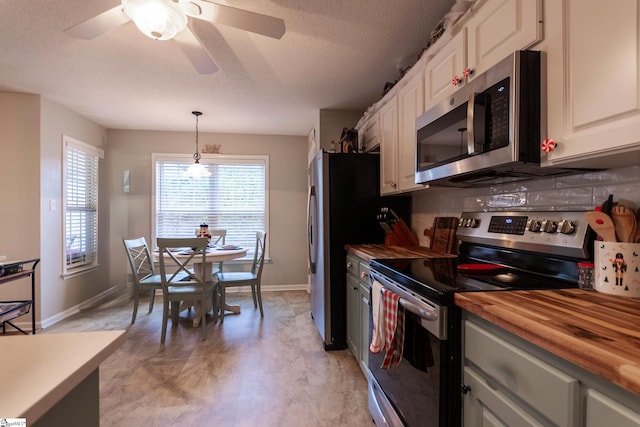 kitchen with wooden counters, tasteful backsplash, stainless steel appliances, pendant lighting, and white cabinetry