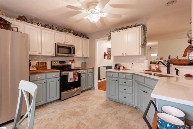 kitchen featuring ceiling fan, sink, stainless steel appliances, gray cabinets, and white cabinets