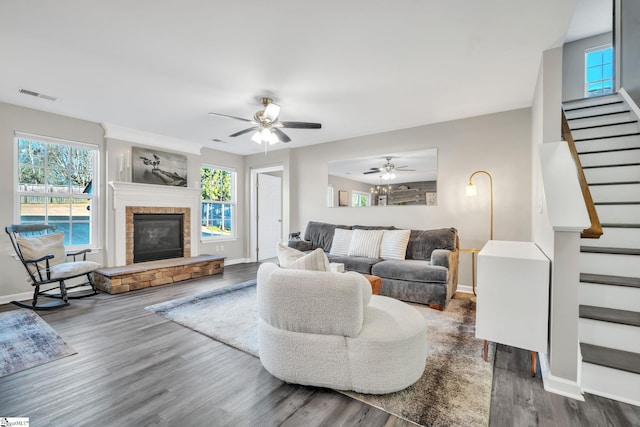 living room featuring ceiling fan, dark hardwood / wood-style floors, a fireplace, and a wealth of natural light