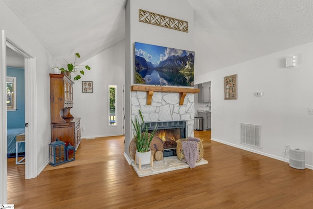 living room with hardwood / wood-style flooring, lofted ceiling, and a fireplace