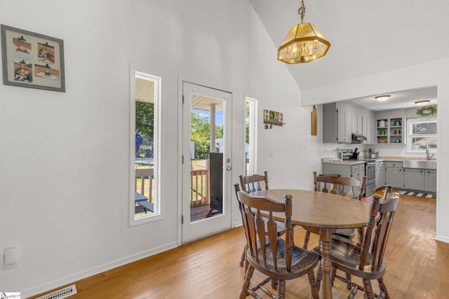 dining area featuring light hardwood / wood-style flooring, a chandelier, vaulted ceiling, and sink