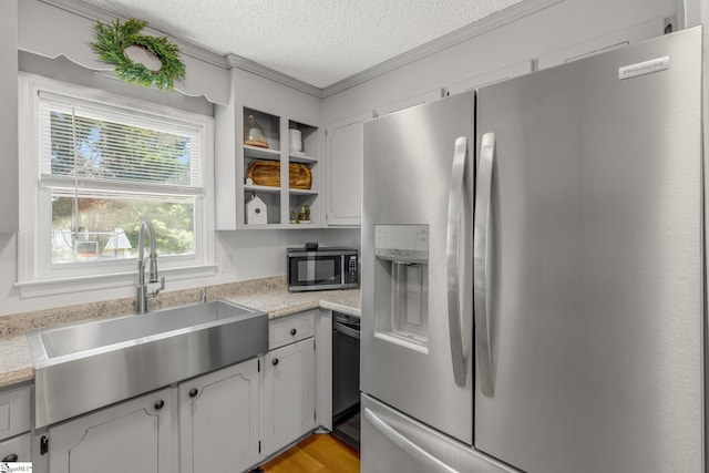 kitchen with a textured ceiling, stainless steel appliances, sink, light hardwood / wood-style flooring, and white cabinets