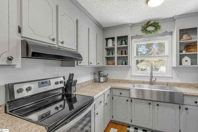 kitchen with a textured ceiling, sink, stainless steel electric range, and light hardwood / wood-style flooring