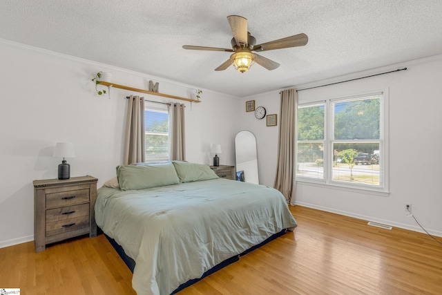 bedroom featuring ceiling fan, light hardwood / wood-style floors, crown molding, and a textured ceiling