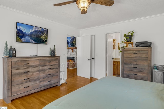 bedroom with ensuite bath, ornamental molding, a textured ceiling, ceiling fan, and hardwood / wood-style flooring