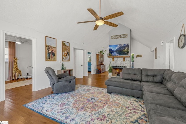 living room with wood-type flooring, a stone fireplace, ceiling fan, and plenty of natural light