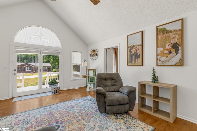 living area with a textured ceiling, hardwood / wood-style flooring, vaulted ceiling, and ceiling fan