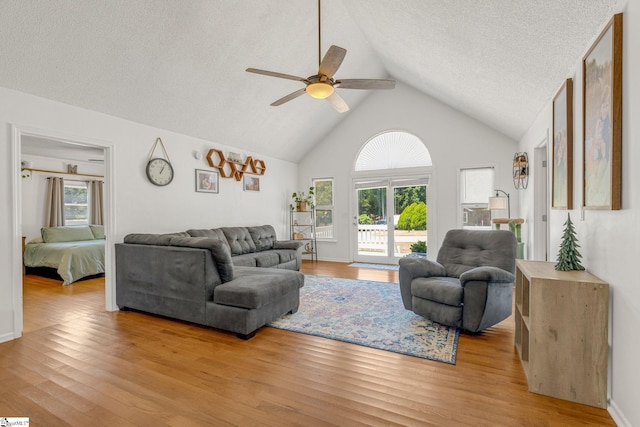 living room featuring a textured ceiling, light hardwood / wood-style floors, ceiling fan, and lofted ceiling