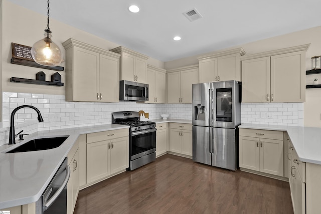 kitchen with pendant lighting, sink, stainless steel appliances, and cream cabinets