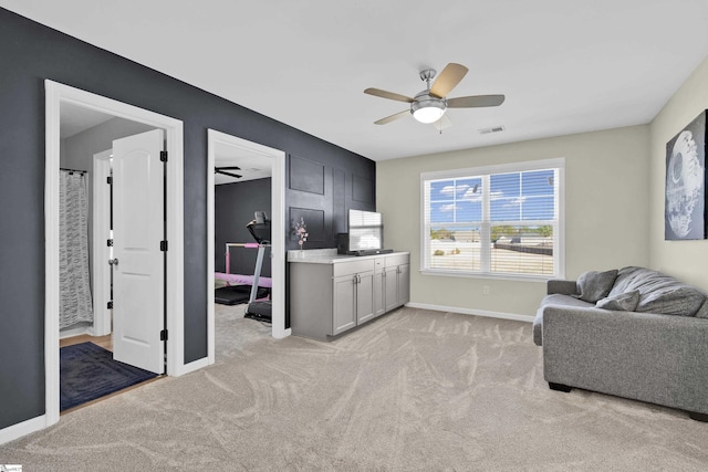 living area featuring light carpet and ceiling fan