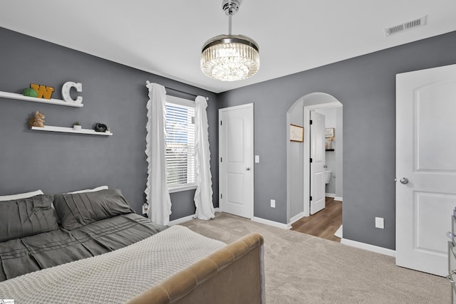 bedroom with a notable chandelier, carpet floors, and ensuite bath